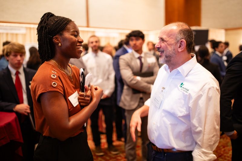 Young woman with dark hair chats with a gentleman wearing a white shirt