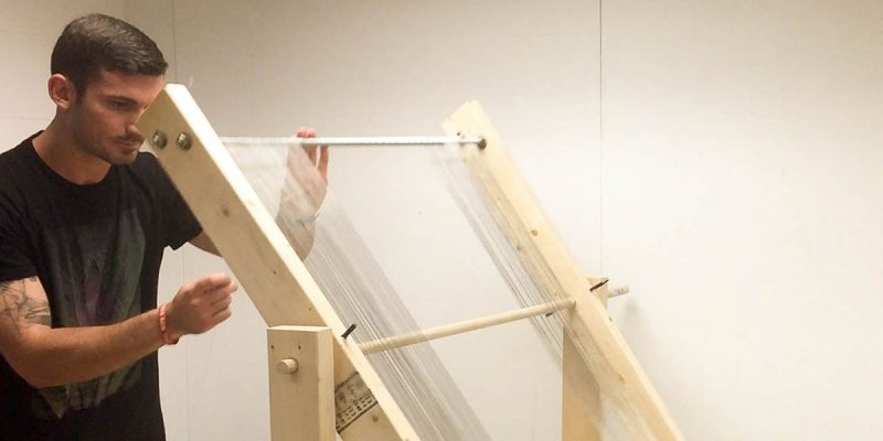 A photo of Josh Tulkoff constructing a large prototype of the fog harp, which consists of a vertical array of 700 wires and is based on initial experimental results.