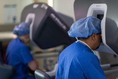 Dr. Kristin McCoy (left), a minimally invasive surgery fellow, and Dr. David Salzberg, a bariatric surgeon, sit at the robot’s consoles. Dr. Salzberg, who performs the majority of his procedures robotically, uses dual consoles for training purposes.