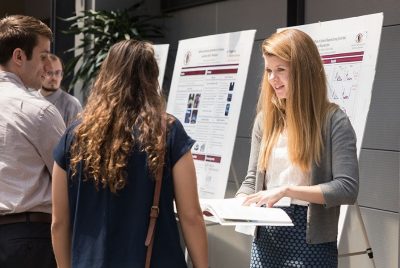 A BEAM graduate student explains her research findings to several onlookers during a presentation