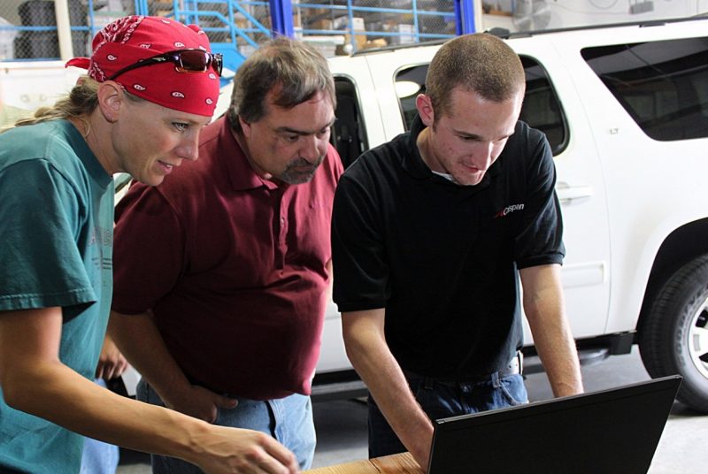 Researchers are training a student on how to conduct vehicle research installations in a garage at the Virginia Tech Transportation Institute.